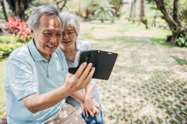 istock Married senior couple using smart phone in park 1188855593