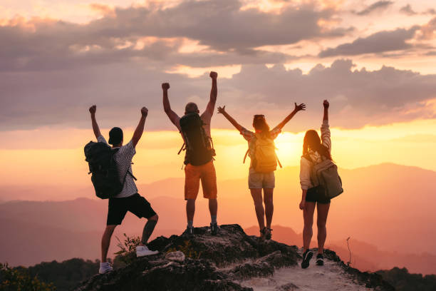 istock Happy hikers tourists with raised arms at sunset 1188856625