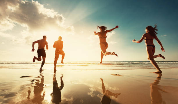 istock Four friends runs at sunset sea beach 1188856742
