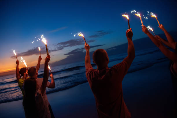 istock Happy friends at sunset beach party with fireworks 1188856905