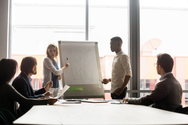 istock Focused young multiracial presenters explaining market research to colleagues. 1188856981