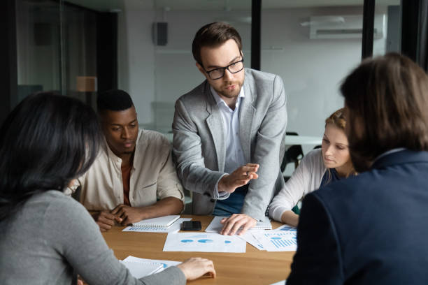 istock Focused confident young employee sharing ideas with focused group. 1188856982