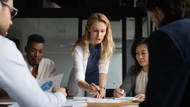 młoda bizneswoman wyjaśniająca wyniki badań na wykresach kolegom. - leadership business women senior adult zdjęcia i obrazy z banku zdjęć