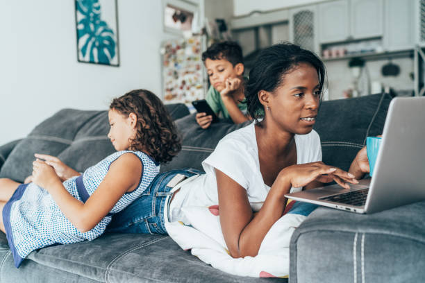 Mixed race family with digital devices Mixed race mother and her two children using digital devices at home family dependency mother family with two children stock pictures, royalty-free photos & images