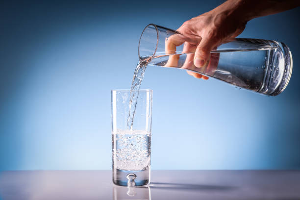 istock Pouring drinking water from a pitcher into a glass. Clean drinkable water concept 1188862878