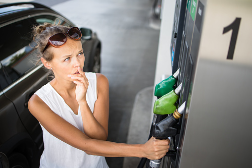 Car pumping gas at gas pump. Closeup of man pumping gasoline fuel in car at gas station.
