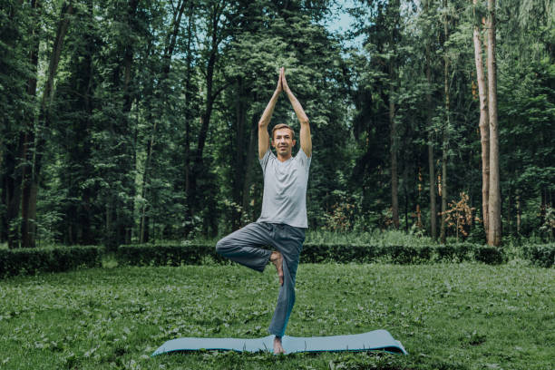 istock Fitness, man training yoga in tree pose in park 1188864591