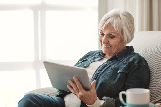 istock Smiling senior woman using a digital tablet at home 1188864598