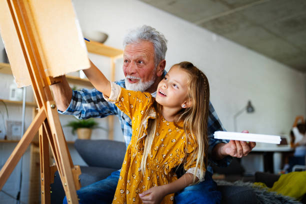 starszy mężczyzna z malowaniem dzieci na płótnie. dziadek spędza szczęśliwy czas z wnuczką. - senior male obrazy zdjęcia i obrazy z banku zdjęć