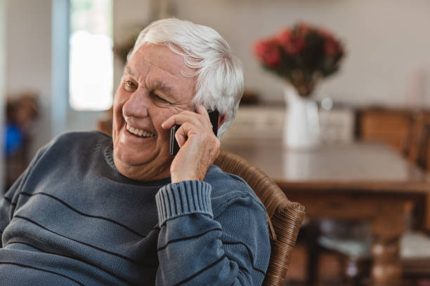 Laughing senior man talking on a cellphone in at home