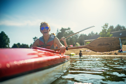 Teenage girl and mother enjoying kayaking on lake on sunny summer day.\nNikon D850