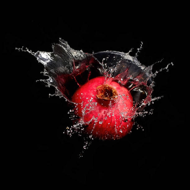 Pomegranate in splash of water isolated on black