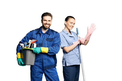 Atractiva mujer y hombre en uniforme de limpieza y guantes de goma sosteniendo un productos de limpieza de escoba en sus manos photo