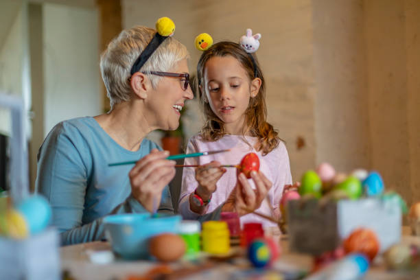 istock Grandmother with granddaughter decorating Easter eggs at home. 1188873429