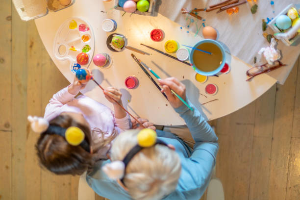 istock Grandmother with granddaughter decorating Easter eggs at home. 1188873471