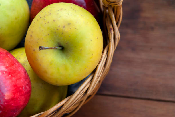 istock Ripe apples in wicker basket on wooden background 1188877629