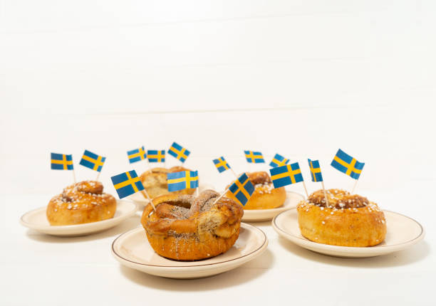 istock Swedish cinnamon buns (kanelbullar) on the white wooden table. Swedish flags. Coffee break (fika) 1188878064