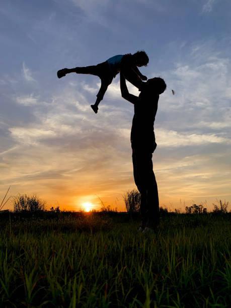 istock Silhouette Father Playing With Son While Standing On Grass Against Sky During Sunset 1188880345