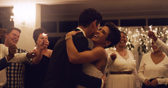 Cropped shot of an affectionate young newlywed couple dancing while their guests are holding up sparklers at their wedding reception
