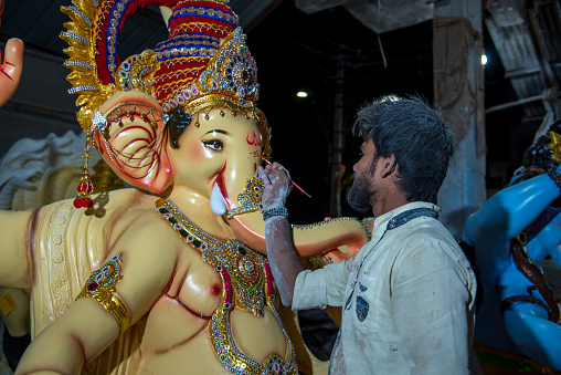 AMRAVATI, MAHARASHTRA - SEPTEMBER 8, 2018: Artist making a statue and gives finishing touches on an idol of the Hindu god Lord Ganesha at an artist's workshop for Ganesha festival.