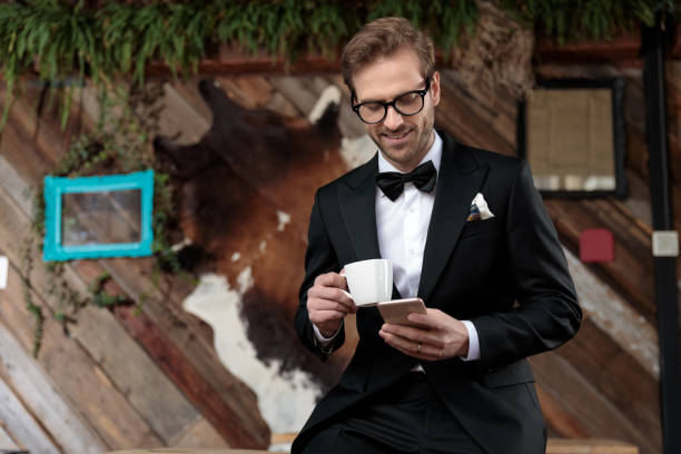 istock Young groom holding a cup and looking at his phone 1188882773