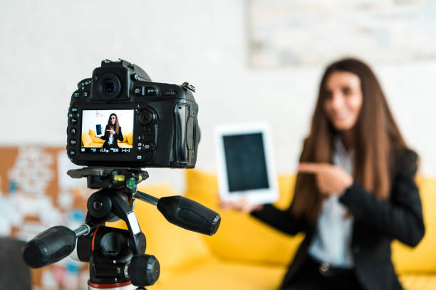 istock selective focus of digital camera with happy video blogger pointing with finger at digital tablet with blank screen 1188882949