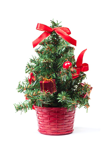 Small artificial christmas tree with red decorations isolated on white