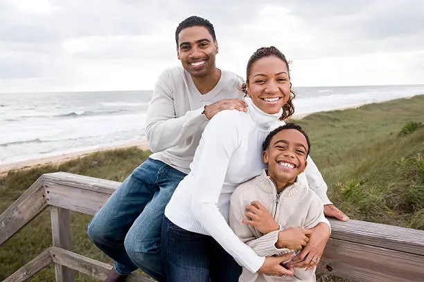 Photo of African-American family smiling and hugging at beach