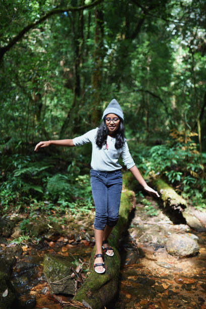 istock Preadolescent girl walking on the fallen tree trunk 1188887383