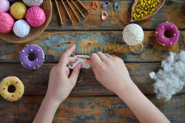istock Making crochet amigurumi donuts. Toy for babies or trinket.  On the table threads, needles, hook, cotton yarn. Handmade gift. Income from hobby. DIY crafts concept. Step 1 - knit all details. 1188889233