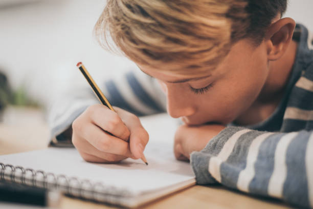 istock Close-Up Of Boy Making Sketch On Note Pad At Table 1188889496