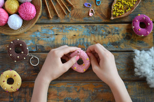 istock Making crochet amigurumi donuts. Toy for babies or trinket.  On the table threads, needles, hook, cotton yarn. Handmade gift. Income from hobby. DIY crafts concept. Step 3 - to sew all details. 1188890070