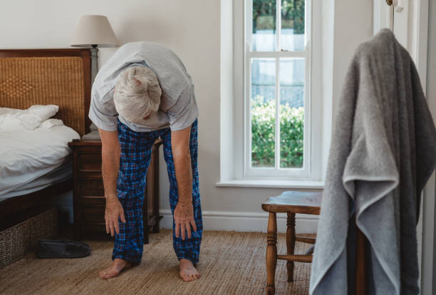 homme aîné faisant des étirements après se réveiller le matin - se courber en avant photos et images de collection