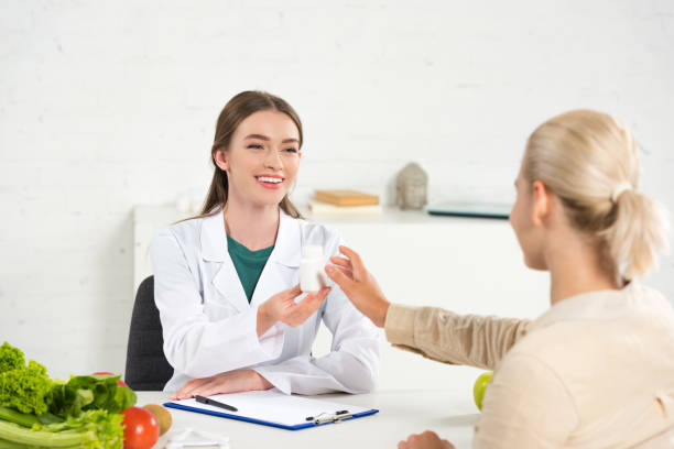 istock smiling dietitian in white coat giving pills to patient at table 1188890552