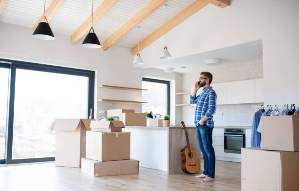 istock Mature man with boxes moving in new house, using smartphone. 1188890765
