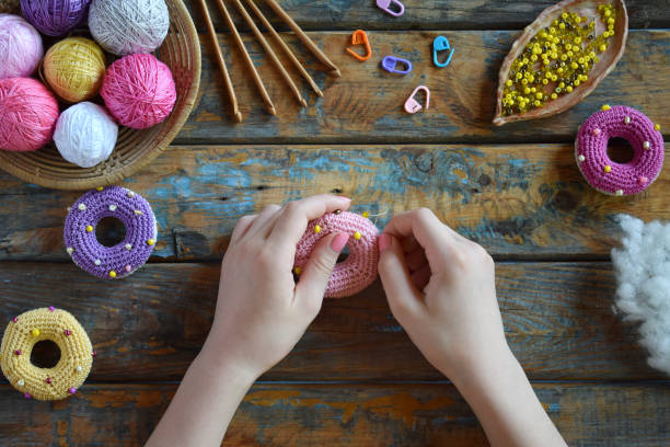 istock Making crochet amigurumi donuts. Toy for babies or trinket.  On the table threads, needles, hook, cotton yarn. Handmade gift. DIY crafts concept. Step 2. Stuff the toy with padding polyester. 1188893681