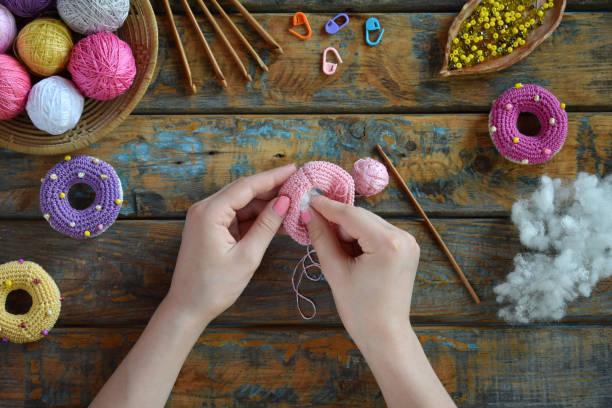 istock Making crochet amigurumi donuts. Toy for babies or trinket.  On the table threads, needles, hook, cotton yarn. Handmade gift. DIY crafts concept. Step 2. Stuff the toy with padding polyester. 1188894118