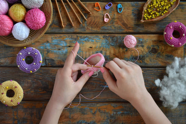 istock Making crochet amigurumi donuts. Toy for babies or trinket.  On the table threads, needles, hook, cotton yarn. Handmade gift. Income from hobby. DIY crafts concept. Step 1 - knit all details. 1188894136