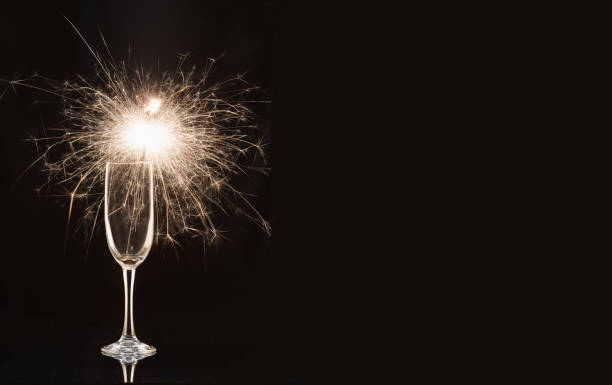 Champagne glass with lit sparkler against a dark background