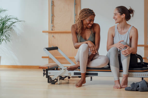 파이에이트 개혁가에 앉아 있는 두 여성 - pilates machine 뉴스 사진 이미지