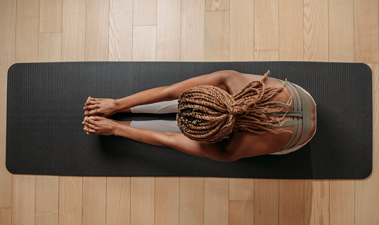 Overhead photo of sportswoman doing stretching exercise on fitness mat.