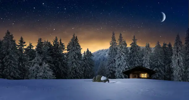 Illuminated log cabin in winter night