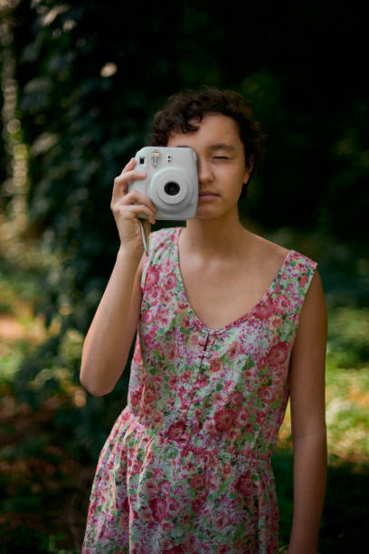 istock Smiling girl taking photo on instant camera in forest 1188901808