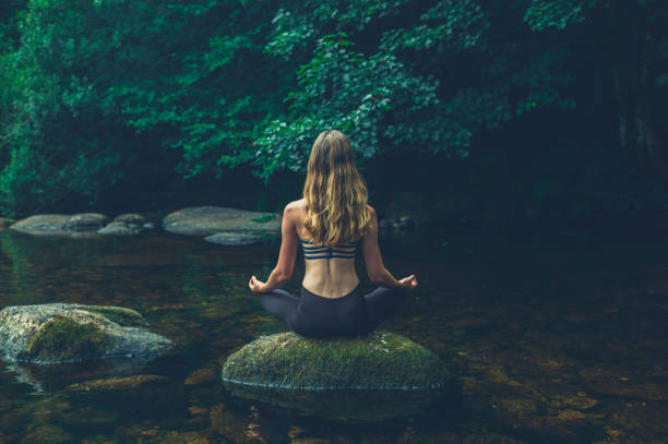 istock Woman meditating on rock in river 1188903052