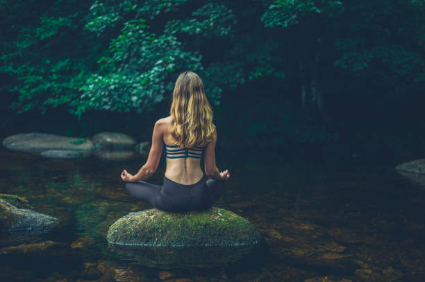 istock Woman meditating on rock in river 1188903320