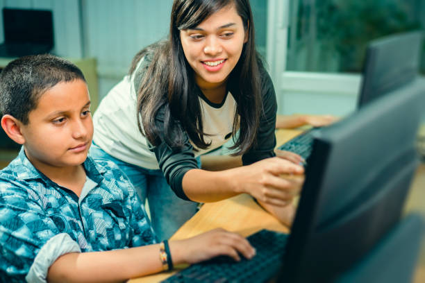 행복 한 여성 젊은 성인 교사 가르쳐 남성 십 대 학생 에 a 컴퓨터 클래스. - computer lab child internet development 뉴스 사진 이미지