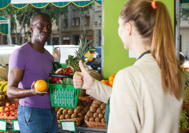 istock Young seller is helping client choose oranges 1188908367