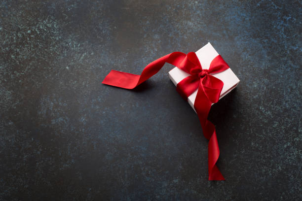 istock White Gift box with red ribbon on red background 1188909869