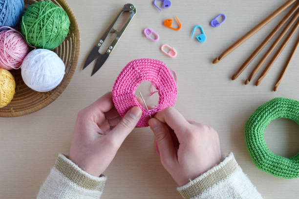 istock Making crochet pyramid from colored rings. Toy for babies and toddlers to learn mechanical skills and colors. On the table threads, needles, hook, cotton yarn. Handmade crafts. DIY concept. 1188911480