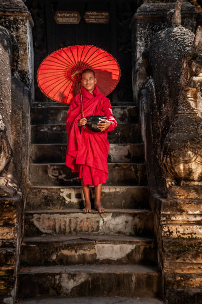 Young Buddhist monk standing next to temple, Bagan, Myanmar Young Buddhist monk posing next to one of ancient temples in Bagan, Myanmar (Burma) bagan archaeological zone stock pictures, royalty-free photos & images